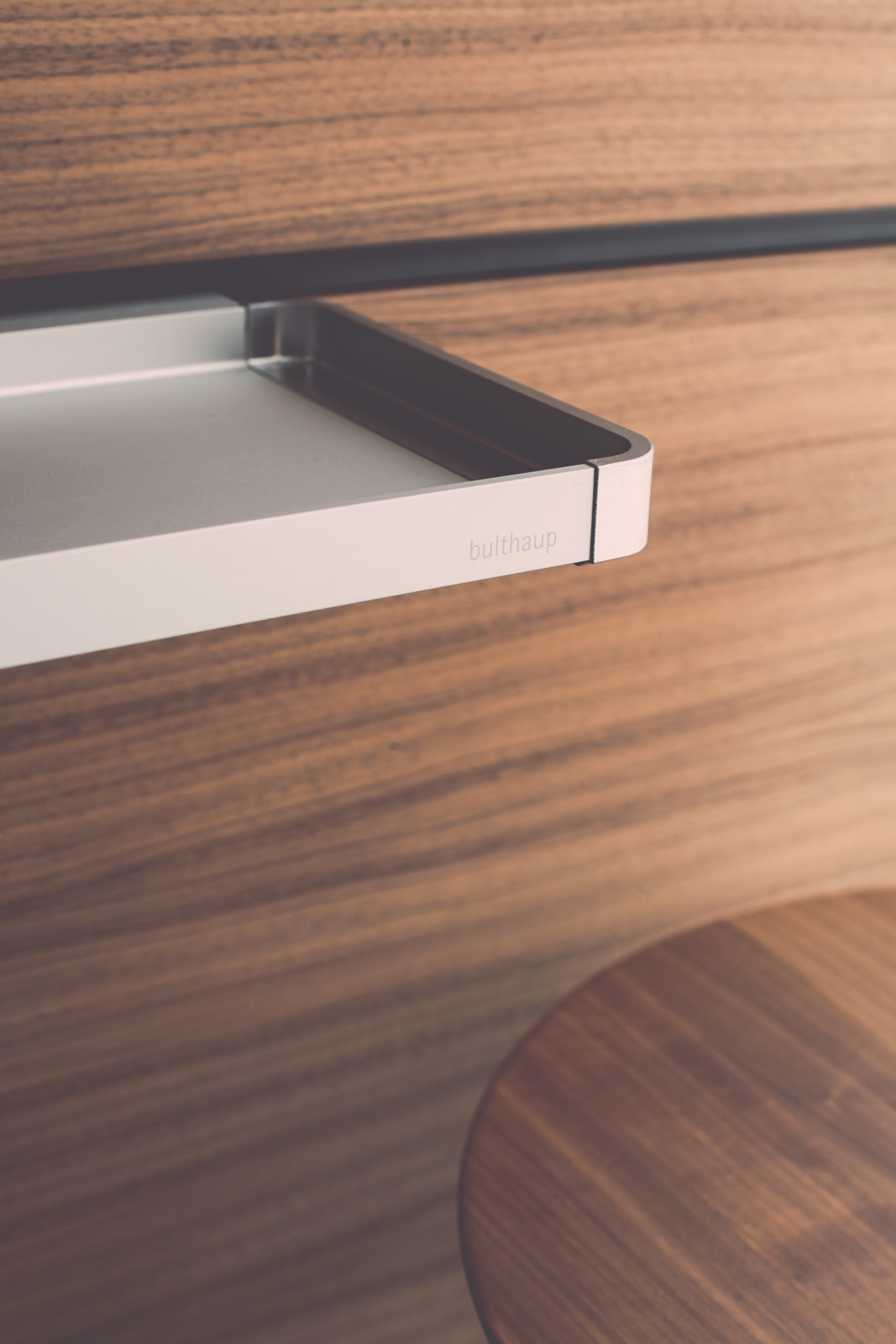 Détail d'un tiroir bulthaup b3 en noyer avec système de rangement intérieur, texture du bois visible