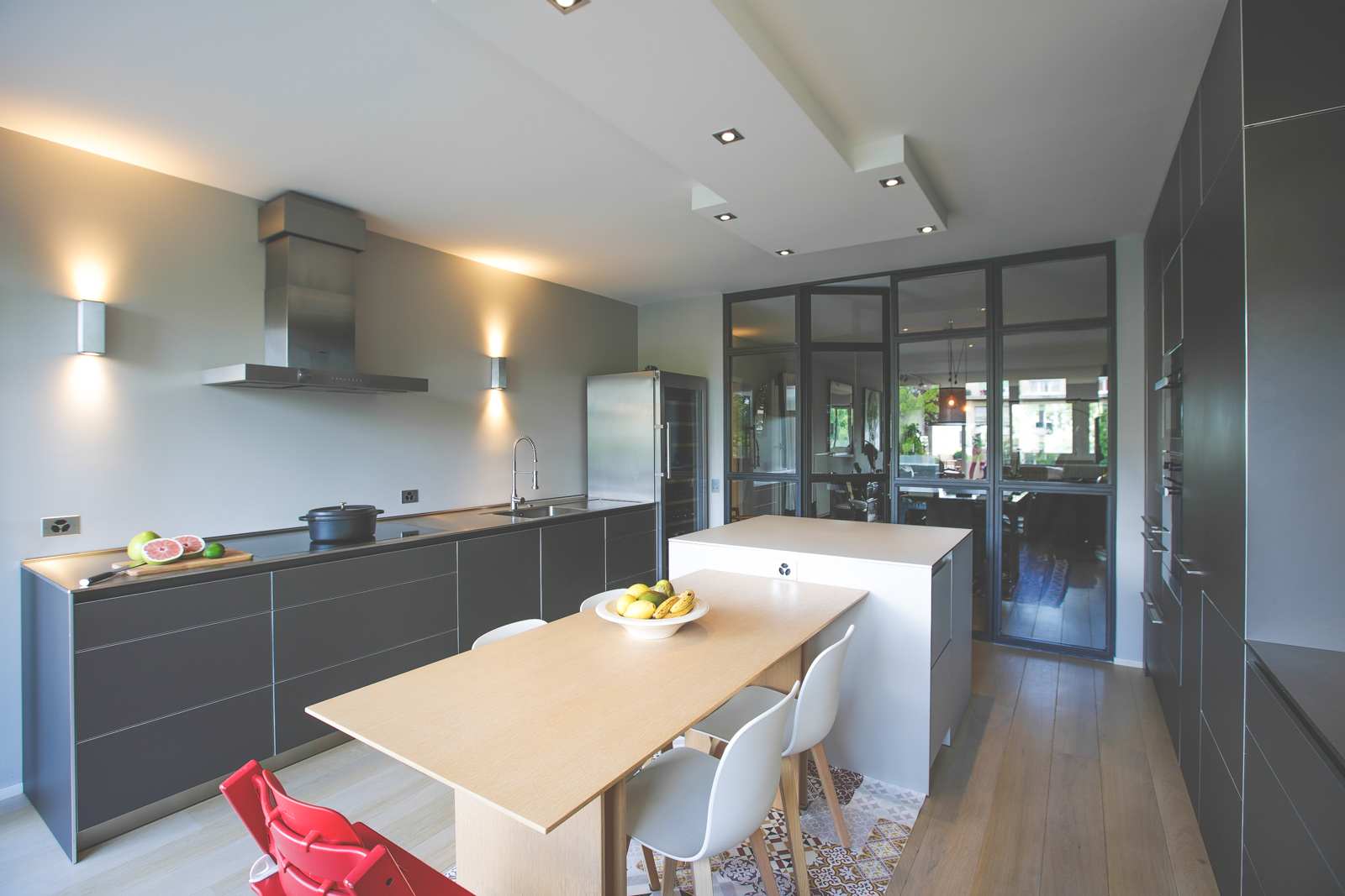 Cuisine bulthaup ouverte sur salle à manger dans un appartement haussmannien avec verrière et carreaux de ciment