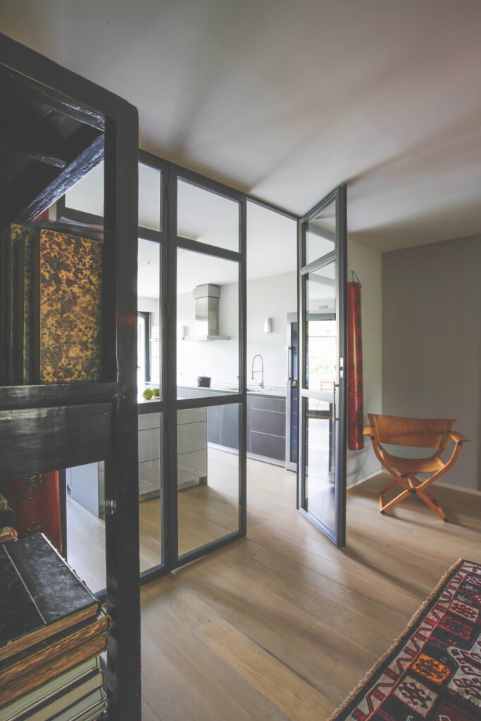 Cuisine bulthaup en L dans un appartement parisien haussmannien avec verrière d'atelier et parquet chêne