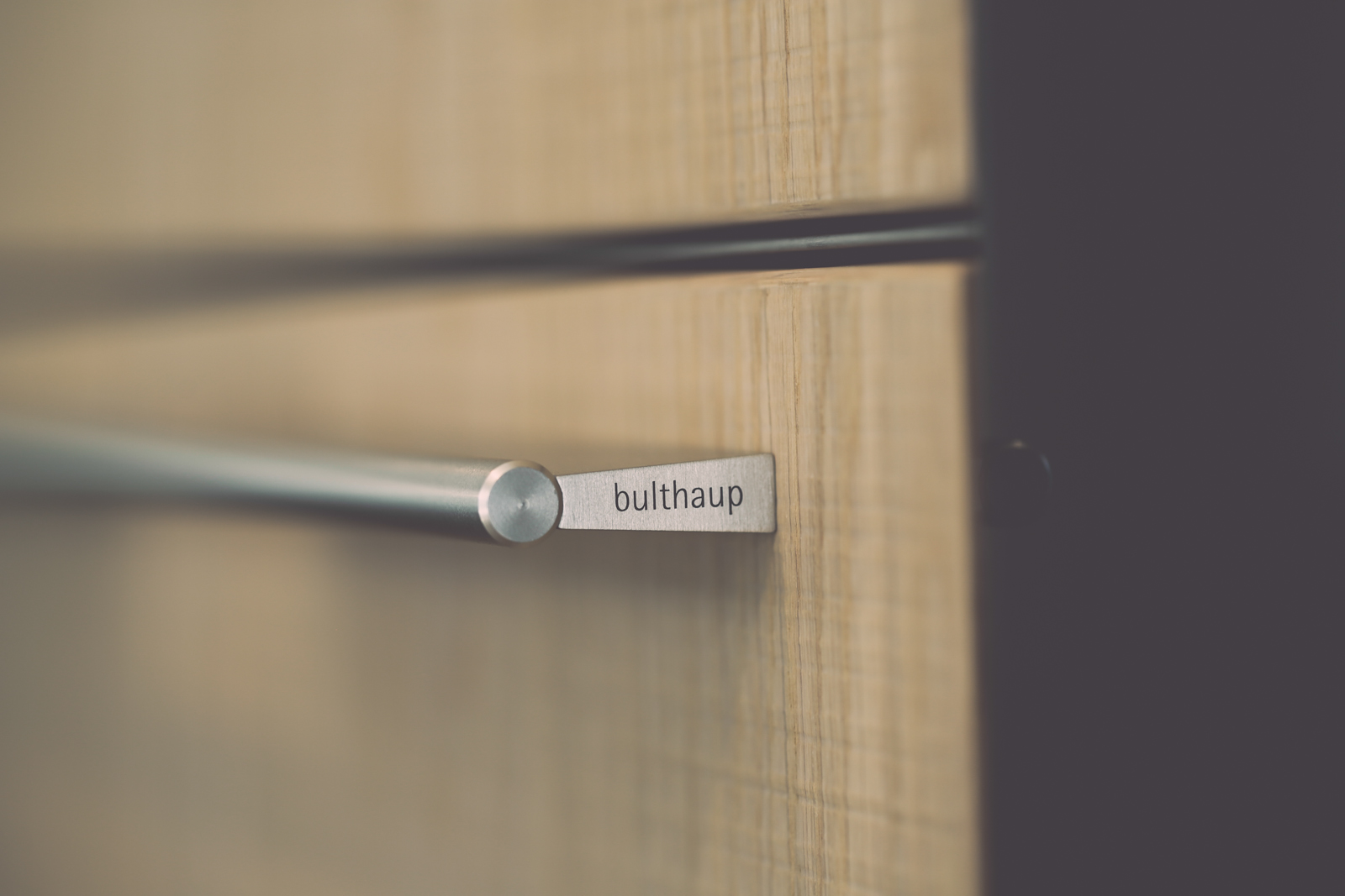Détail d'une poignée bulthaup en bois massif sur façade claire